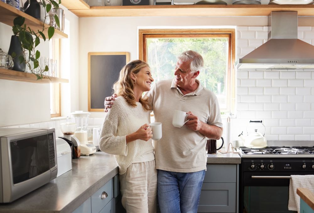 Senior couple standing a their kitchen each holding a cup